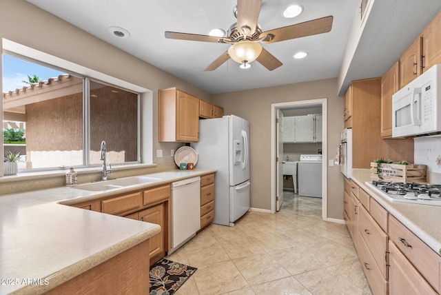 kitchen featuring light countertops, a ceiling fan, a sink, white appliances, and washer / clothes dryer