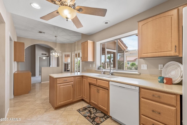 kitchen featuring white dishwasher, a sink, ceiling fan with notable chandelier, light countertops, and a peninsula