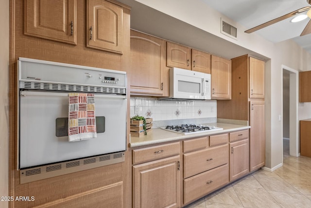 kitchen featuring light brown cabinetry, visible vents, decorative backsplash, white appliances, and light countertops