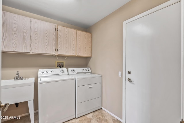 laundry area featuring washing machine and dryer, baseboards, cabinet space, and a sink