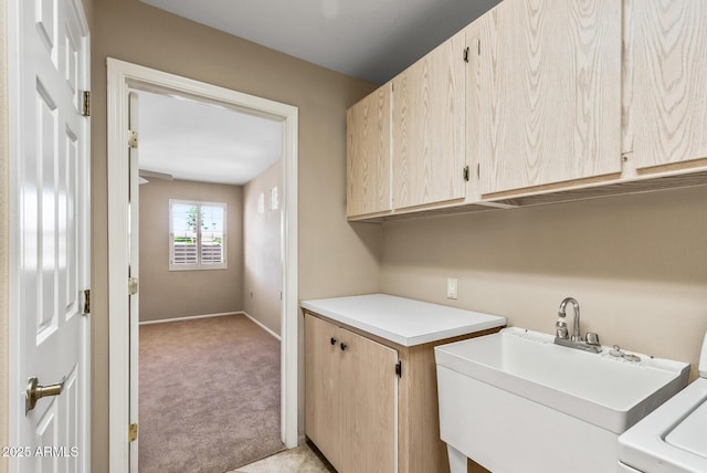 washroom featuring a sink, baseboards, light colored carpet, washer / clothes dryer, and cabinet space