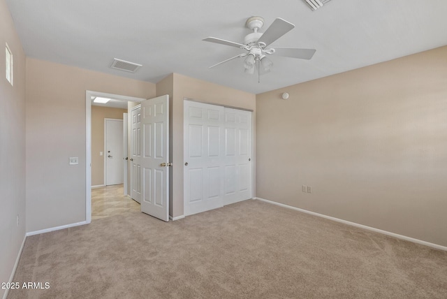 unfurnished bedroom with visible vents, a closet, baseboards, light colored carpet, and ceiling fan