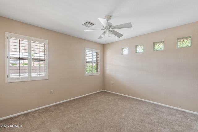 empty room with visible vents, carpet flooring, baseboards, and a ceiling fan