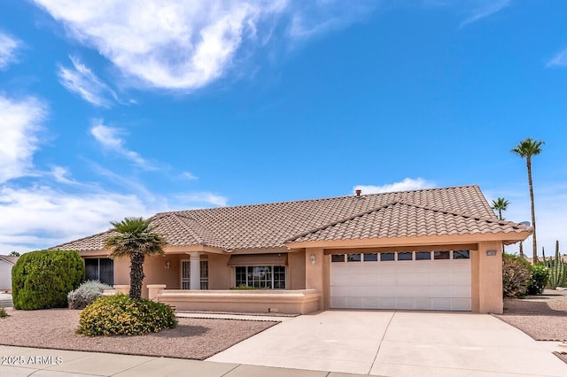 view of front of house with an attached garage, a tiled roof, driveway, and stucco siding