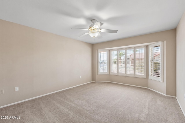 carpeted spare room featuring baseboards and ceiling fan