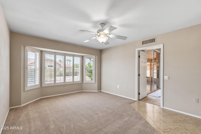 unfurnished room featuring carpet flooring, visible vents, a ceiling fan, and baseboards