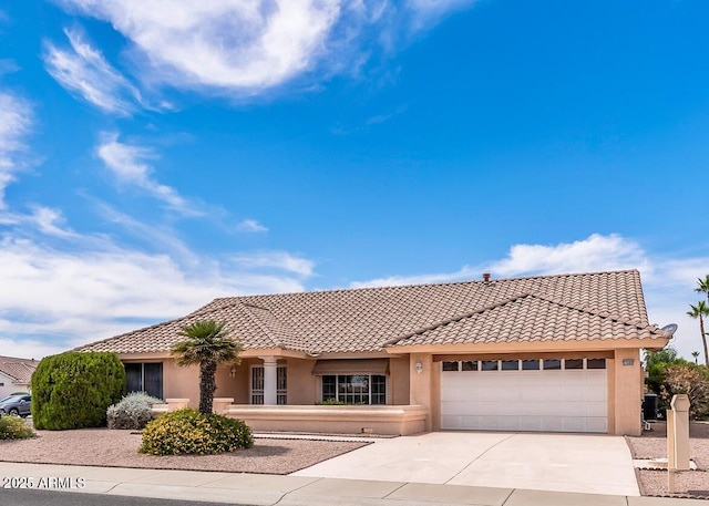 view of front of property featuring a garage, driveway, a tiled roof, and stucco siding