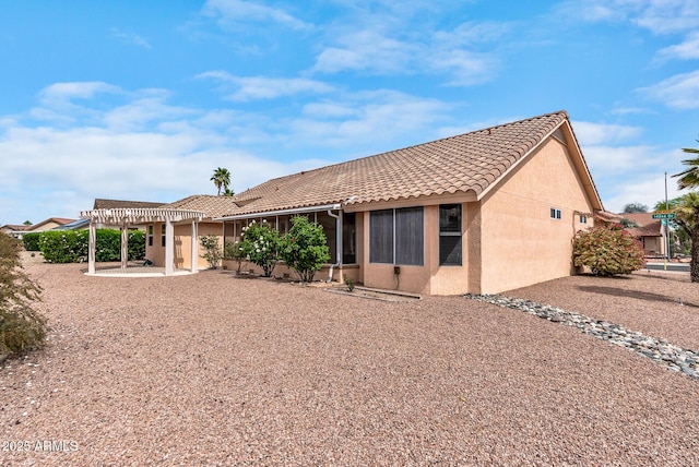 back of house with a pergola, a patio, a tiled roof, and stucco siding