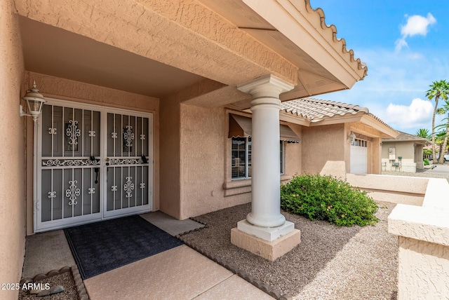 property entrance featuring a garage, a tile roof, and stucco siding