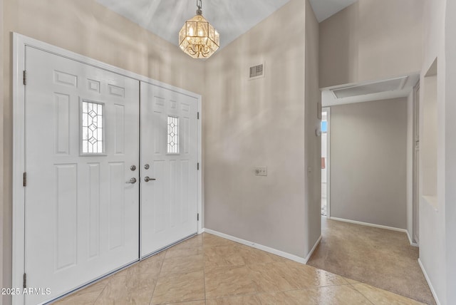 carpeted foyer with an inviting chandelier, visible vents, and baseboards