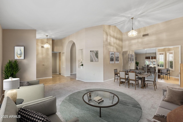 carpeted living room featuring arched walkways, visible vents, and baseboards