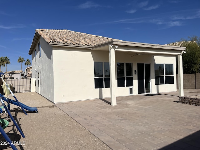 rear view of property with ceiling fan and a patio area