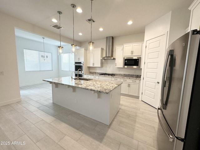 5923 N 85th Ave, Glendale, AZ 85305 - kitchen featuring wall chimney range hood, a kitchen bar, white cabinetry, a sink, and appliances with stainless steel finishes