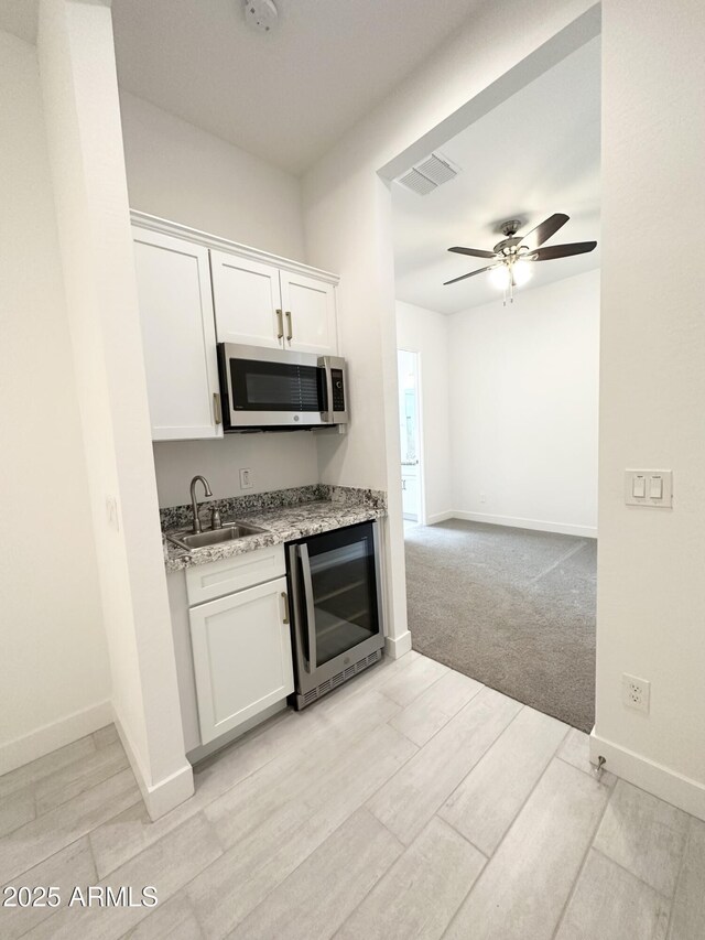 5923 N 85th Ave, Glendale, AZ 85305 - kitchen featuring a sink, beverage cooler, white cabinetry, stainless steel microwave, and a ceiling fan