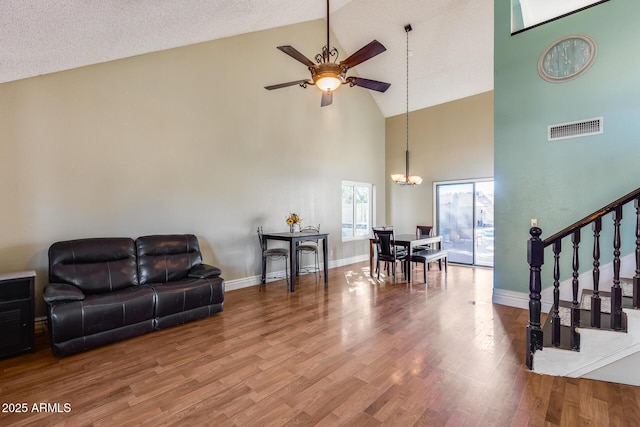 living area with lofted ceiling, wood finished floors, visible vents, baseboards, and stairway