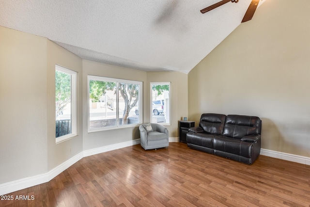 sitting room featuring a textured ceiling, baseboards, vaulted ceiling, and wood finished floors