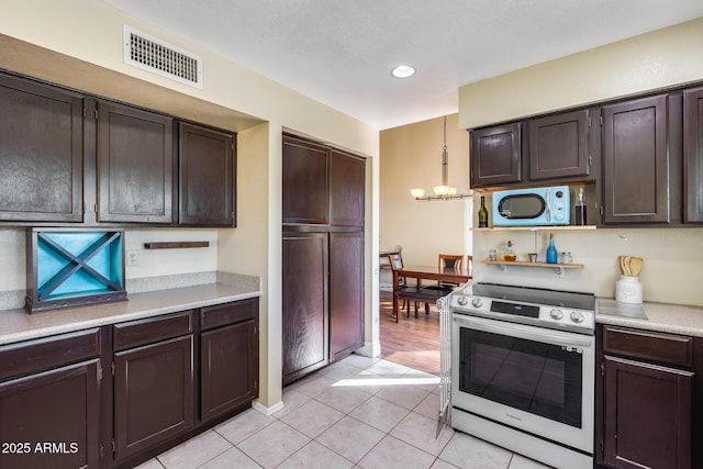 kitchen featuring visible vents, hanging light fixtures, stainless steel electric stove, light countertops, and a chandelier