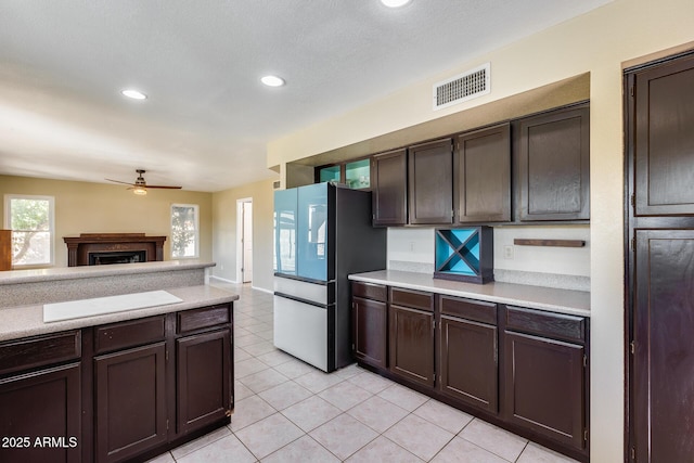 kitchen featuring light tile patterned floors, a fireplace, visible vents, light countertops, and freestanding refrigerator