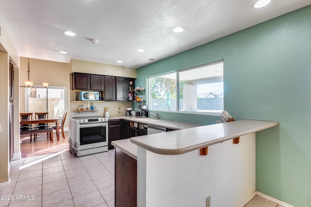 kitchen featuring a peninsula, a breakfast bar, hanging light fixtures, appliances with stainless steel finishes, and light countertops