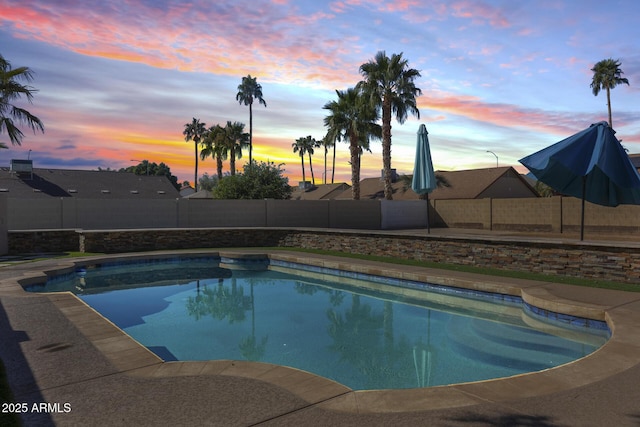 pool at dusk with a fenced backyard and a fenced in pool