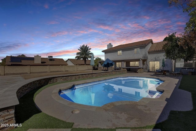 pool at dusk featuring a fenced backyard, a fenced in pool, and a patio