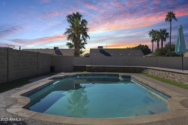 pool at dusk with a fenced backyard and a fenced in pool