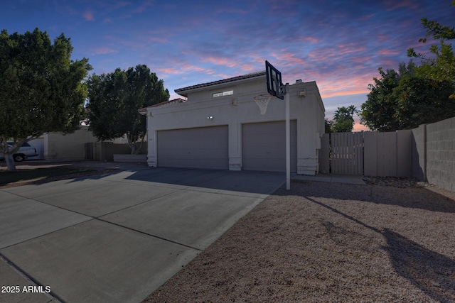 exterior space with driveway, an attached garage, fence, and stucco siding