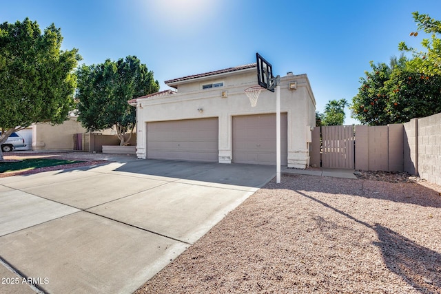 view of front of home featuring concrete driveway, an attached garage, a gate, fence, and stucco siding