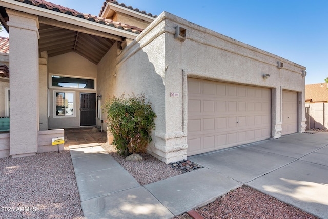 exterior space featuring a garage, a tiled roof, and stucco siding