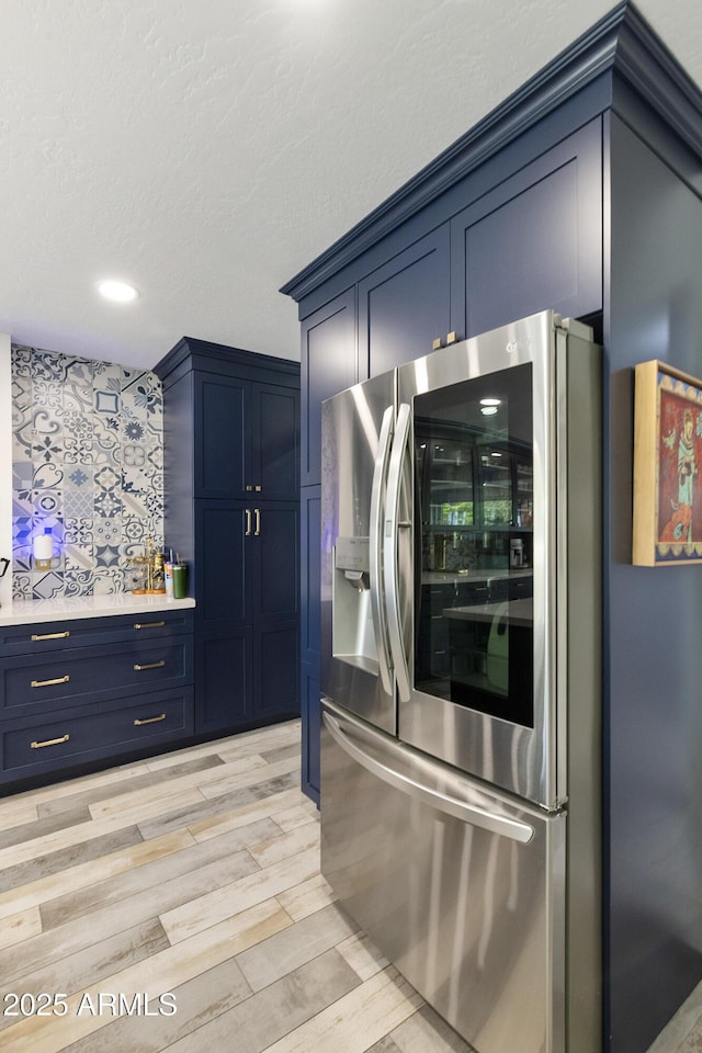1656 W Meseto Cir, Mesa, AZ 85202 - kitchen with stainless steel fridge, blue cabinetry, light wood finished floors, light countertops, and recessed lighting