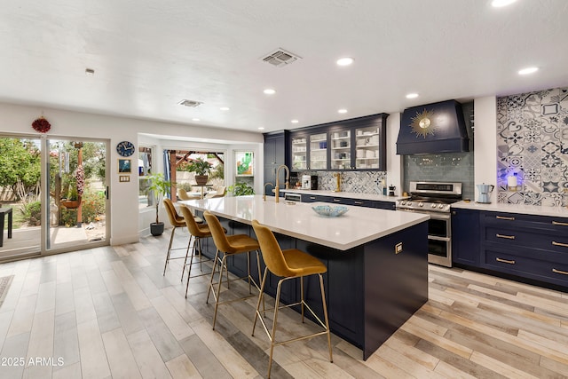 1656 W Meseto Cir, Mesa, AZ 85202 - kitchen with double oven range, premium range hood, a breakfast bar, light countertops, and light wood finished floors