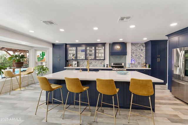1656 W Meseto Cir, Mesa, AZ 85202 - kitchen featuring appliances with stainless steel finishes, decorative backsplash, custom range hood, light countertops, and a large island with sink