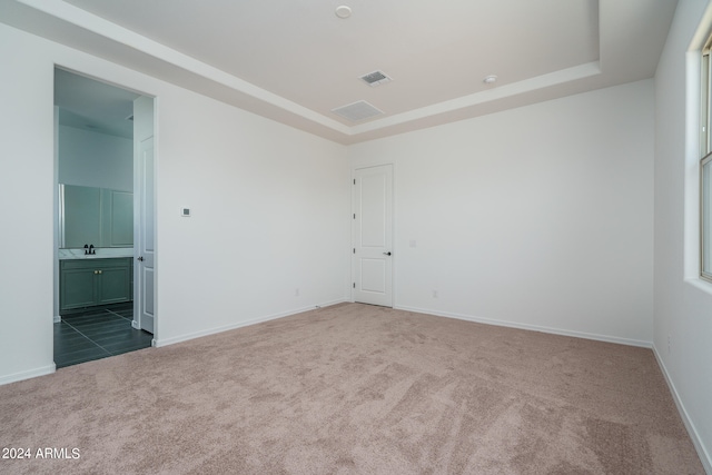 spare room with a tray ceiling and carpet