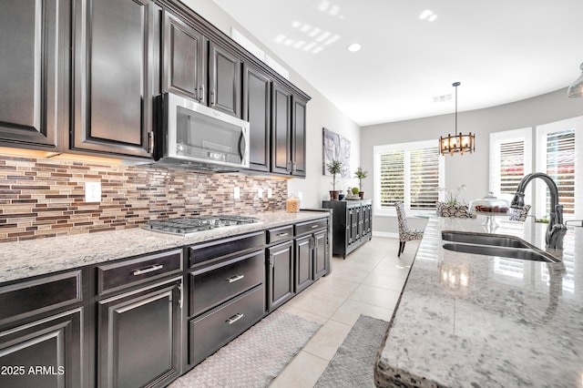 kitchen with sink, light tile patterned floors, stainless steel appliances, light stone counters, and tasteful backsplash