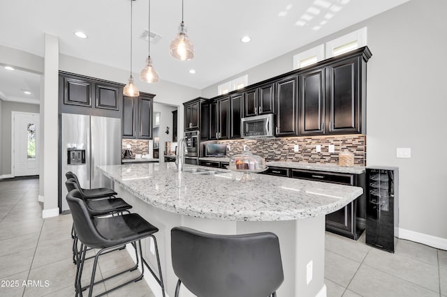 kitchen featuring wine cooler, hanging light fixtures, a large island with sink, and appliances with stainless steel finishes