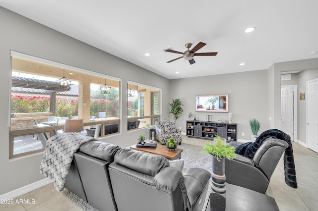 tiled living room with ceiling fan with notable chandelier