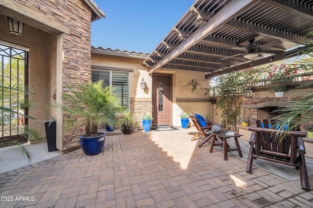 view of patio with an outdoor stone fireplace and a pergola