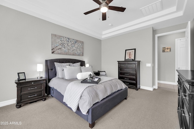 carpeted bedroom with ceiling fan and a tray ceiling