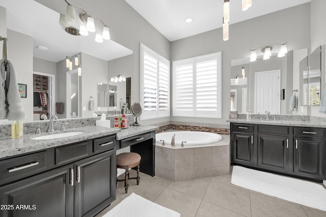 bathroom with tile patterned flooring, vanity, and a relaxing tiled tub