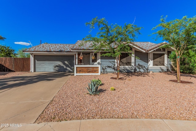 view of front of property featuring a garage, concrete driveway, a tiled roof, and fence