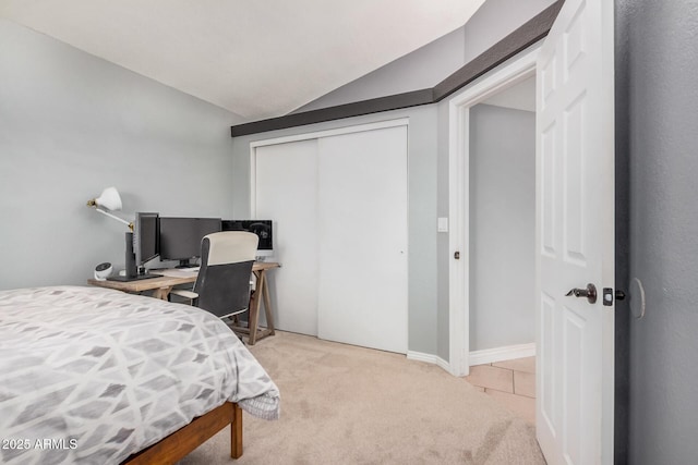 bedroom featuring light colored carpet, a closet, and vaulted ceiling