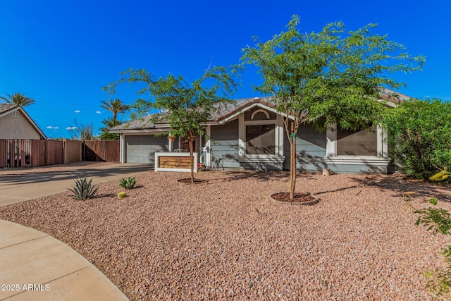 view of front facade featuring concrete driveway, fence, and a garage