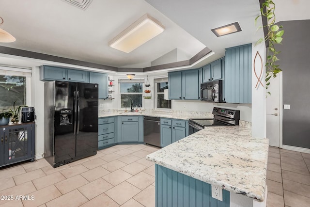 kitchen with black appliances, blue cabinetry, light tile patterned flooring, a peninsula, and a sink