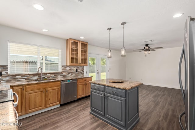 kitchen with ceiling fan, a center island, light stone counters, backsplash, and appliances with stainless steel finishes