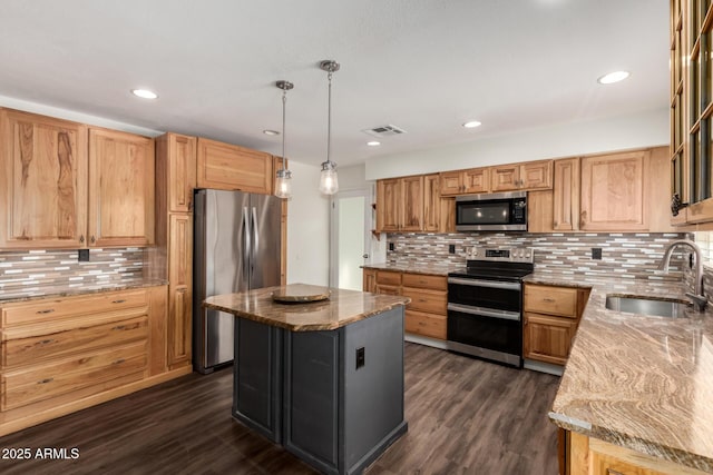 kitchen featuring light stone countertops, stainless steel appliances, sink, a center island, and hanging light fixtures