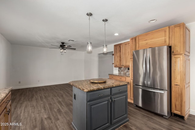 kitchen featuring gray cabinetry, ceiling fan, backsplash, stainless steel fridge, and a kitchen island