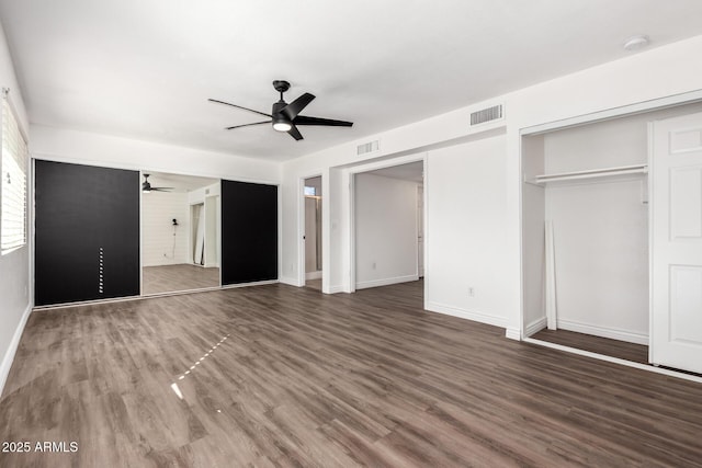 unfurnished bedroom with ceiling fan and dark wood-type flooring