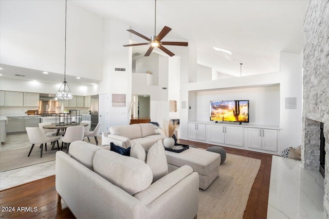 living room featuring dark hardwood / wood-style floors, ceiling fan, a fireplace, and high vaulted ceiling