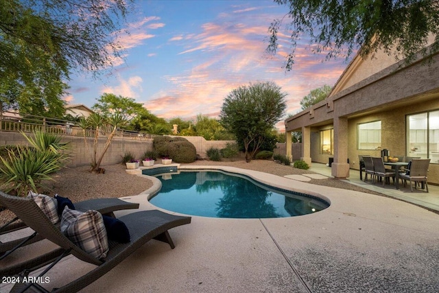 pool at dusk featuring a patio area