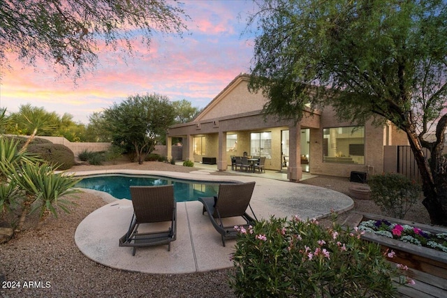 pool at dusk with a patio area